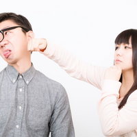 頬をつねられて顔をしかめる彼氏と笑顔の彼女の写真