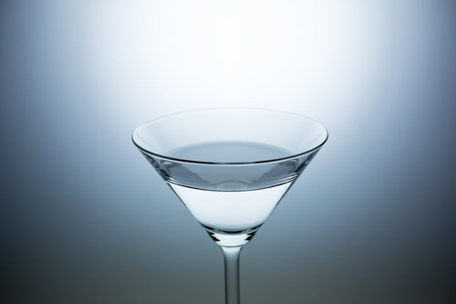 無地背景に置かれた透明なカクテルグラス