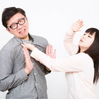 両手を前に出して彼氏を拒絶するピンクの服の彼女の写真