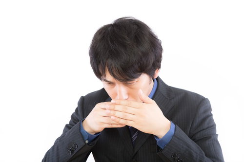 口元を両手で覆う黒ストライプスーツの男性の上半身