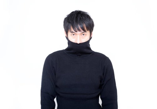 黒い縦線タートルネックの首元を引き上げて口元を隠す男性