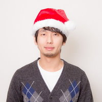 サンタ帽をかぶったカーディガン姿の男性の写真
