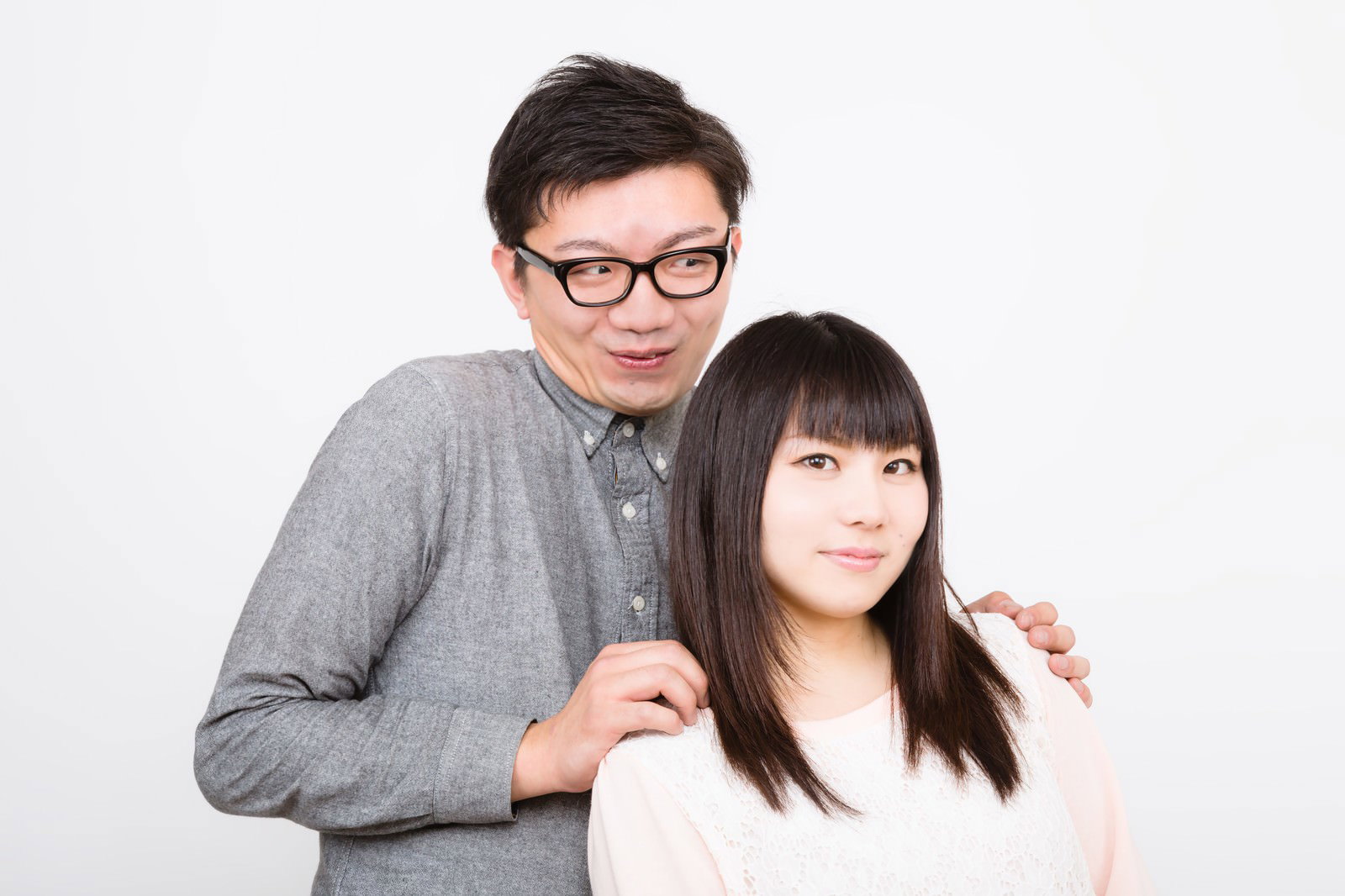 白背景で女性の肩に手を置く下心丸出しの眼鏡の男性［モデル：OZPA Lala］