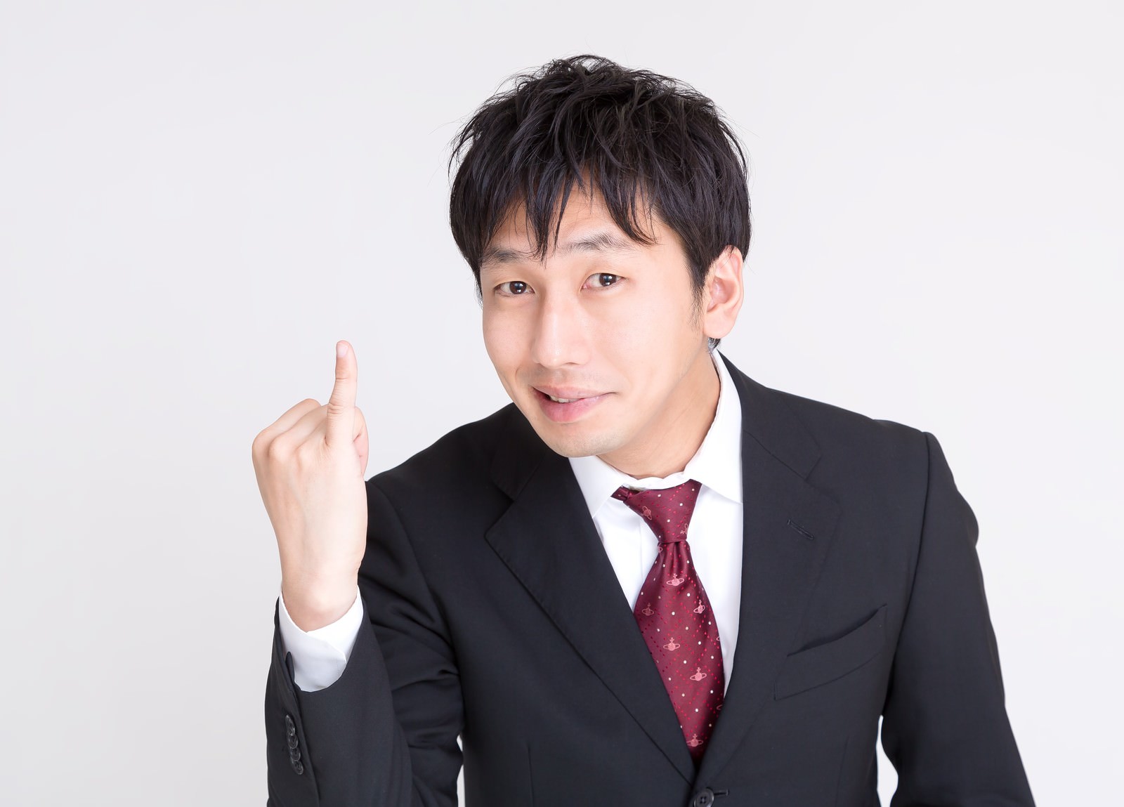 セクハラで免職となった男性がスーツ姿で指を立てるジェスチャーをしている［モデル：大川竜弥］