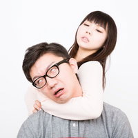 背後から首に腕を回すチョークスリーパーの彼女と彼氏の写真