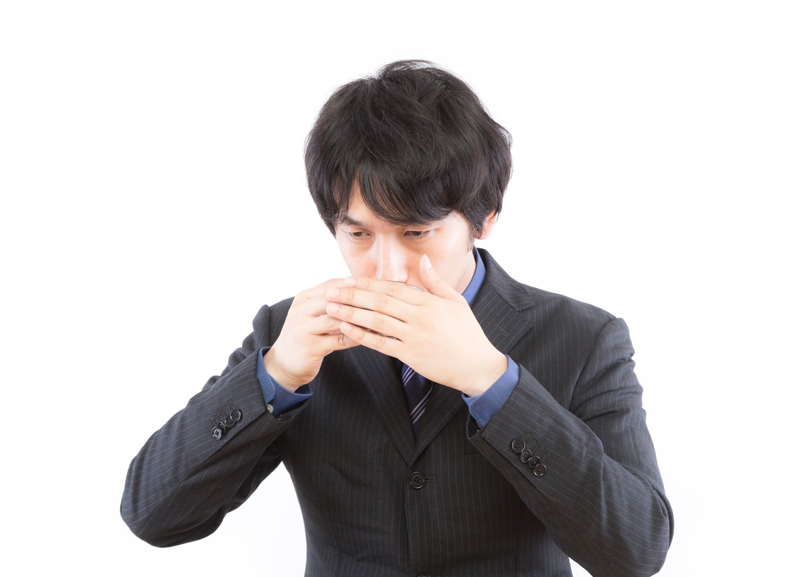 両手で口元を覆うスーツ姿の男性［モデル：大川竜弥］