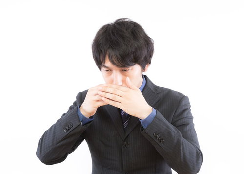 両手で口元を覆うストライプスーツの黒髪の男性