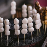 黒い台の上に串に刺さった白い丸い団子が並ぶ接写の写真