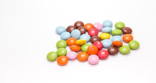 白い平面に散らばるカラフルなマーブルチョコ