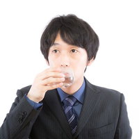 質疑応答の合間にのどを潤す男性の写真