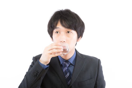 質疑応答の合間にのどを潤す男性