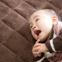 仰向けで口を開ける赤ちゃんの写真