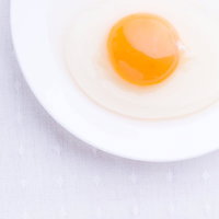 白いお皿の上に割った生たまごの写真