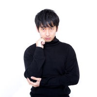 黒いタートルネックで顎に手を当てて立つ男性のポートレートの写真