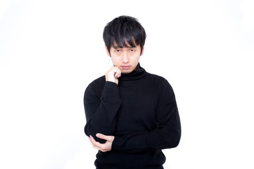 黒いタートルネックで顎に手を当てて立つ男性のポートレート