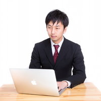 MBAで日報を入力する黒いスーツの男性の写真