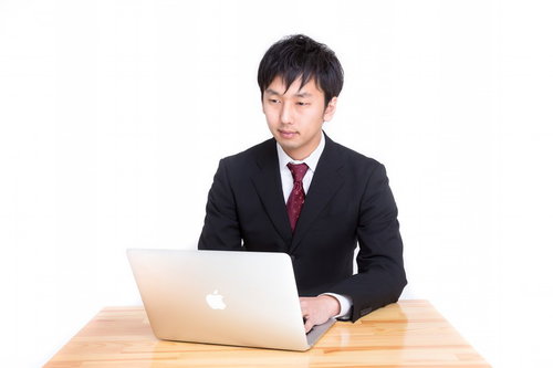 MBAで日報を入力する黒いスーツの男性