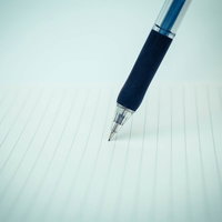 罫線ノートの上に置かれたボールペンの写真