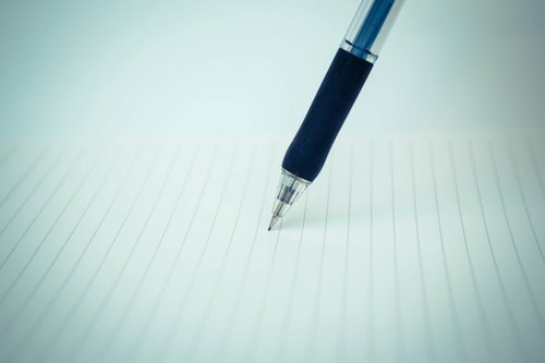 罫線ノートの上に置かれたボールペン