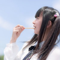 屋外でお菓子を食べるツインテールの女の子の写真