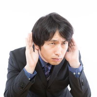 具体的な追求をされると聞こえないふりをする男性の写真
