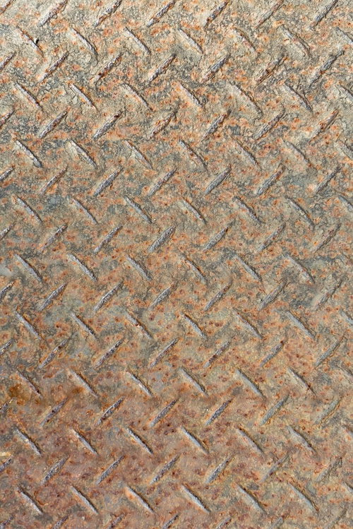 斜めの凸凹模様に錆や汚れが付いた使い込まれた金属板のテクスチャー