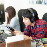 職場で漫画を読みながら仕事をするエンジニア男性の写真