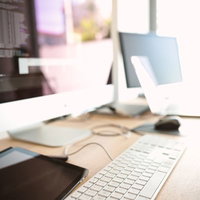 白いキーボードとマウスが並ぶコーディング中のデスクの写真