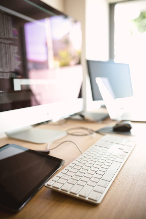 白いキーボードとマウスが並ぶコーディング中のデスク