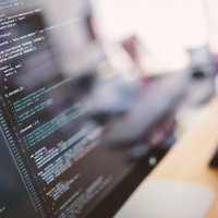 オレンジと水色の文字が並ぶコーディング中のモニターの写真