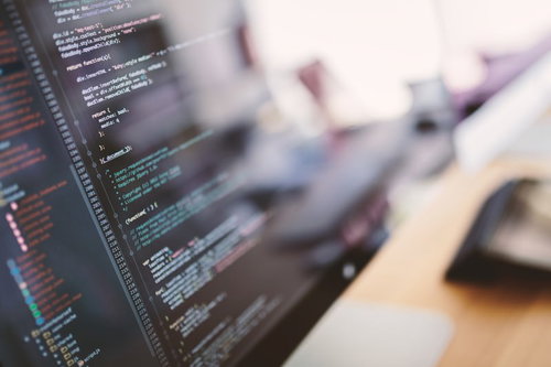 オレンジと水色の文字が並ぶコーディング中のモニター