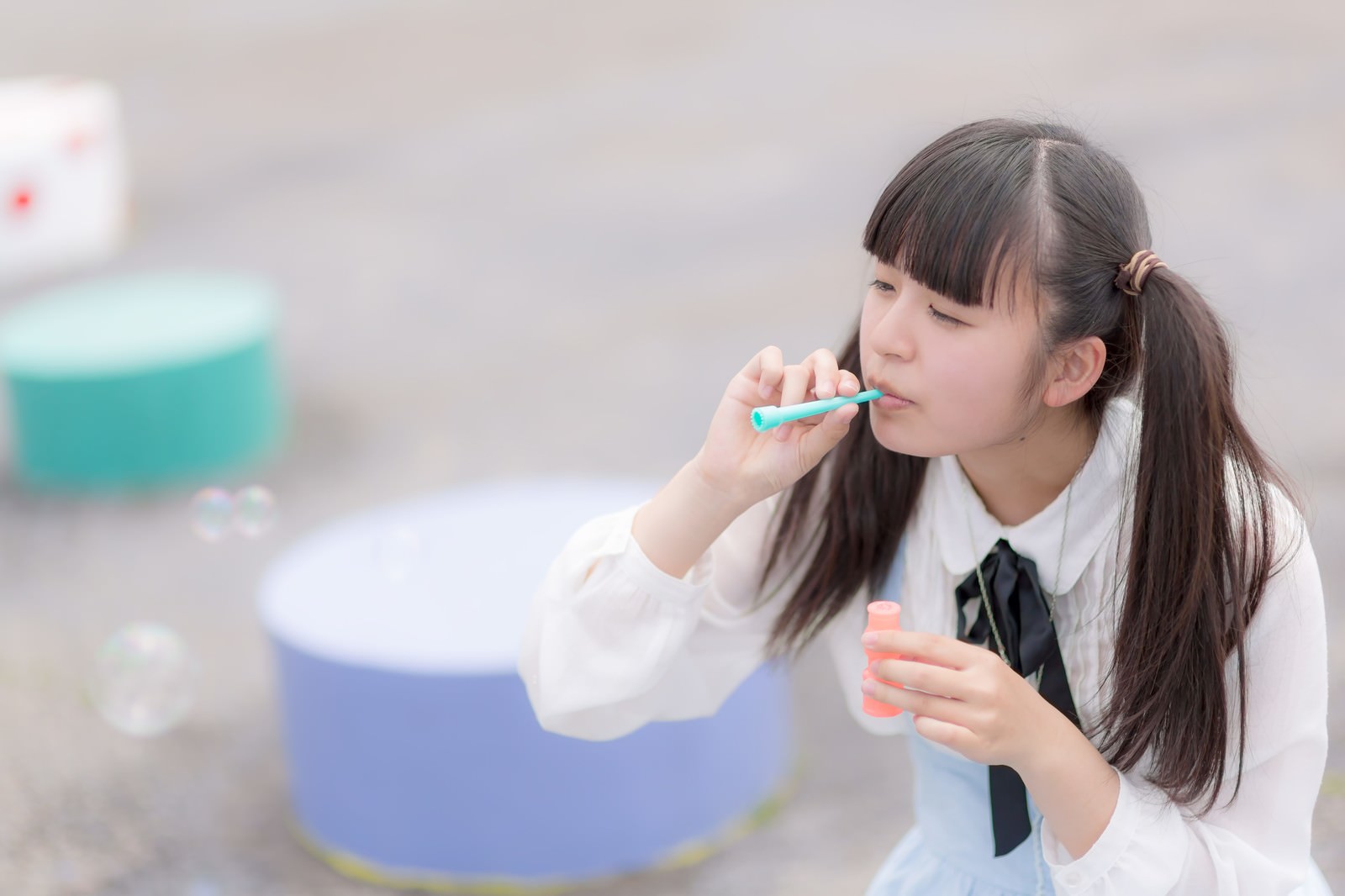 緑のストローでシャボン玉を吹くツインテールの女の子［モデル：こころ］