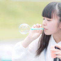 ぷーっとシャボン玉を膨らませるツインテールの女の子の写真