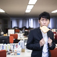残業中トーストを食べ気合を入れる新卒社員の写真