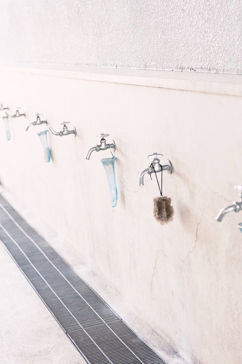白い壁に並ぶ銀色の蛇口と手洗い場