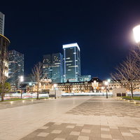 石畳の広場に街灯と樹木が並び奥に高層ビルが見える夜の東京駅前の写真