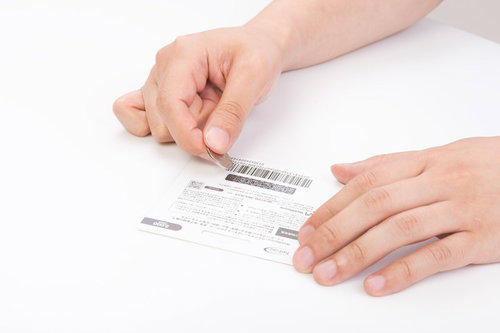 バーコード付きカードを両手で持つ手元の俯瞰