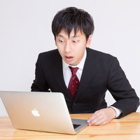 PCを見て「ヤバいことになった」っと驚く表情のビジネスマンの写真