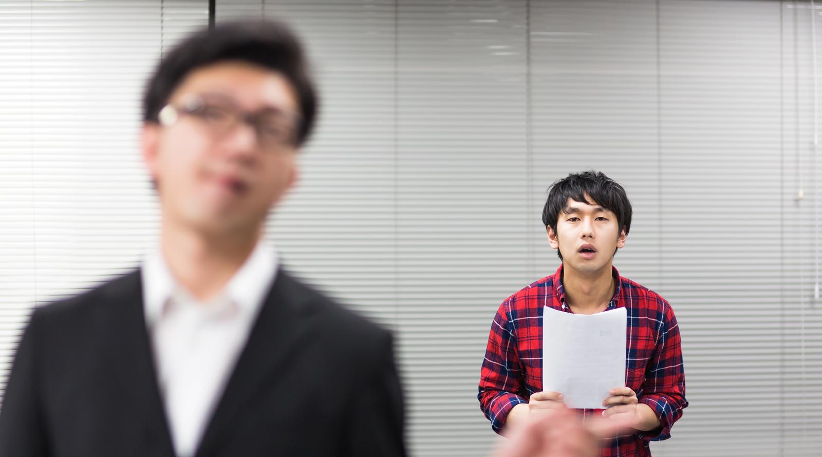 白い紙を持って唖然とするチェック柄シャツのデザイナー［モデル：大川竜弥 OZPA］