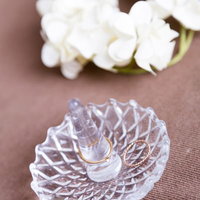 ガラス皿に置かれた金色の結婚指輪と白い花の写真