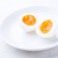 熱湯で8分間茹でた半熟たまご（縦割り）白い皿盛りの写真