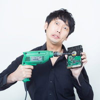 電動ドリルとハードディスクを持って目を見開く黒シャツの男性の写真