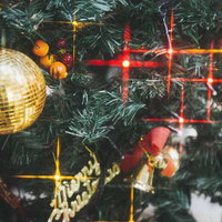 緑の枝に金色のミラーボールやオレンジの飾りが付いたクリスマスツリーの写真