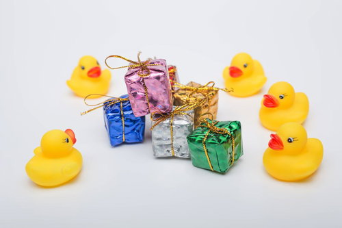 プレゼント箱を囲むアヒルのおもちゃ5羽