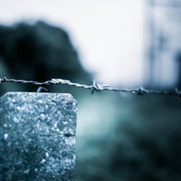 コンクリート柱に張られた有刺鉄線の進入禁止の写真