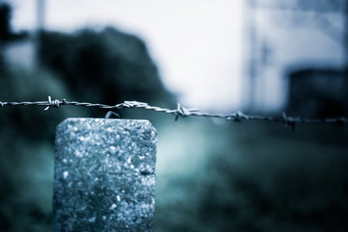 コンクリート柱に張られた有刺鉄線の進入禁止