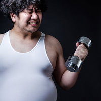 ダンベルよりも贅肉が重そうな肥満男子のトレーニングの写真