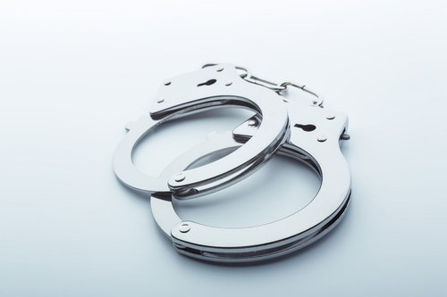 白い面の上に開いた状態で置かれた鎖付きの金属製手錠