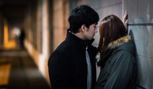 夜間の高架下で彼女に壁ドンをする男性