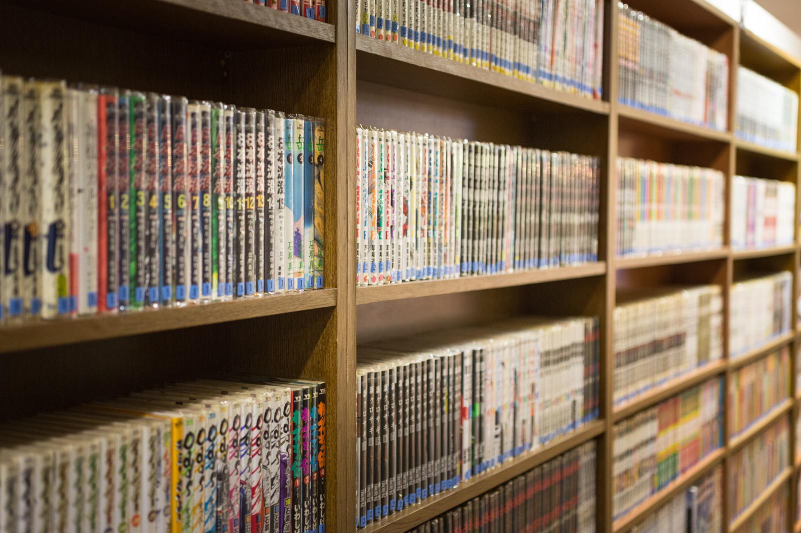 多数の漫画本が色とりどりに並ぶ木製の本棚